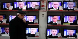 A customer stands next to the TV screens - Ziarul National