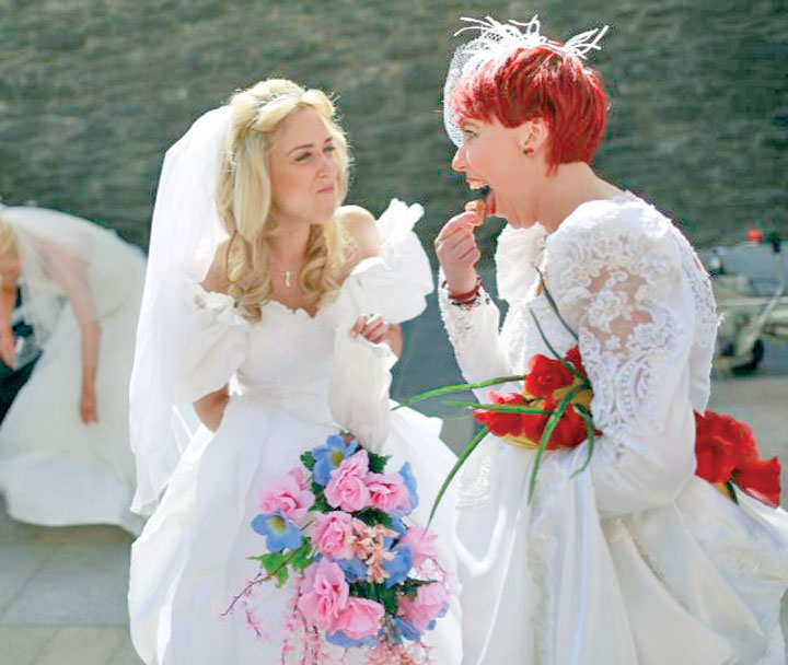 A participant eats a doughnut in Guildhall Square at the "Brides Across the Bridge" event in Londonderry - Ziarul National