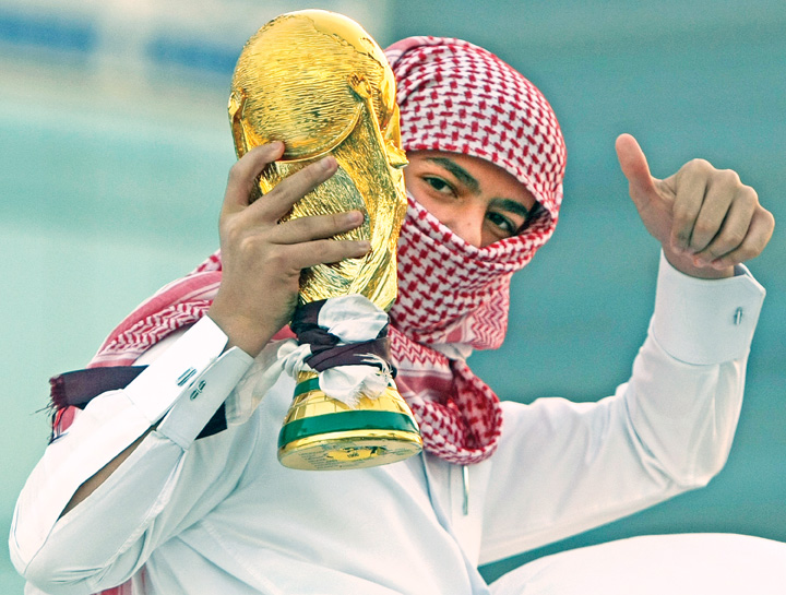 A Qatari youth holds a mock World Cup tr
