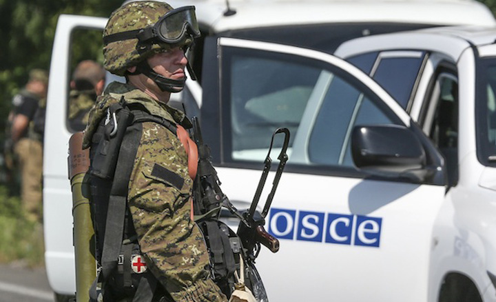 An armed pro-Russian separatist looks next to an OSCE monitoring mission in Ukraine vehicle, on the way to the site where the downed Malaysia Airlines flight MH17 crashed, outside Donetsk - Ziarul National