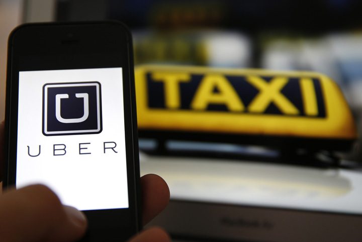 File illustration picture showing the logo of car-sharing service app Uber on a smartphone next to the picture of an official German taxi sign - Ziarul National